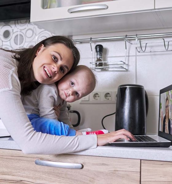 Young mother with toddler in her arms talking online with psychologist, making video call, video conference using laptop at home. Technology, mental health, therapy, distance lifestyle concept